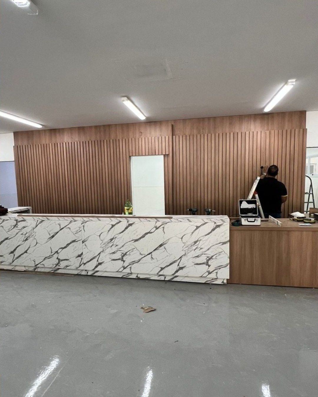 Recepção: Balcão marmorizado e painel ripado